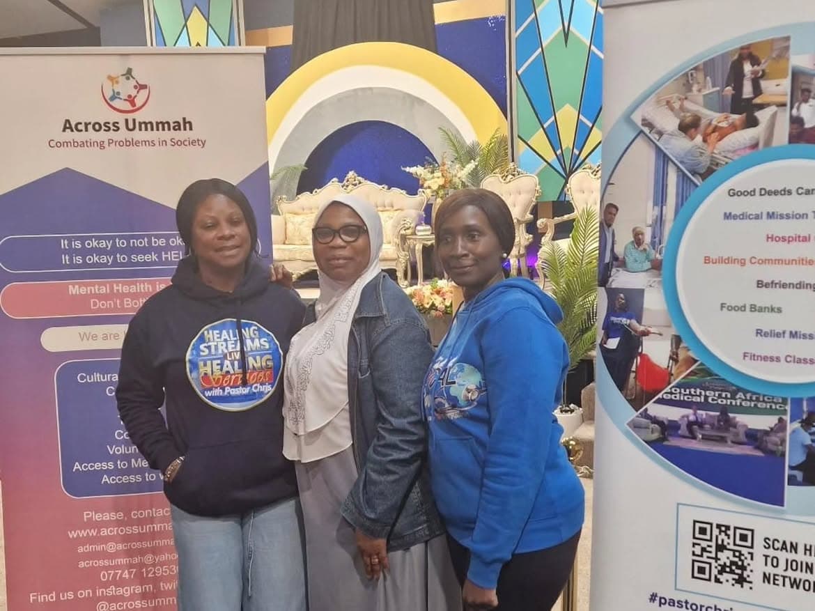 Three women standing together and smiling at an indoor partnership event.